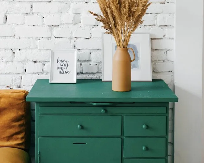 green drawers with a vase and picture frames on top